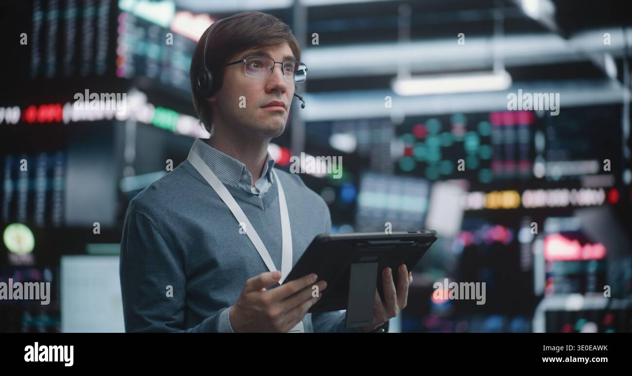 Investment Specialist Analyzing Stock Performance at Advanced Workstation, Standing on Live Trading Floor, Professional Interaction With Mobile Technology. Strategic Planning, Individual Leadership. Stock Photo