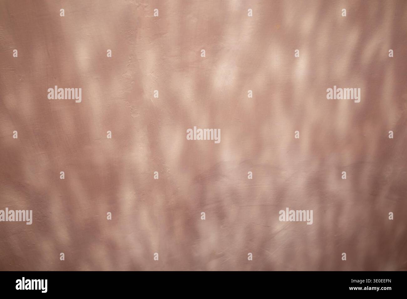 Soft pink wall with abstract light reflection and textured plaster surface creating subtle pattern and mood Stock Photo
