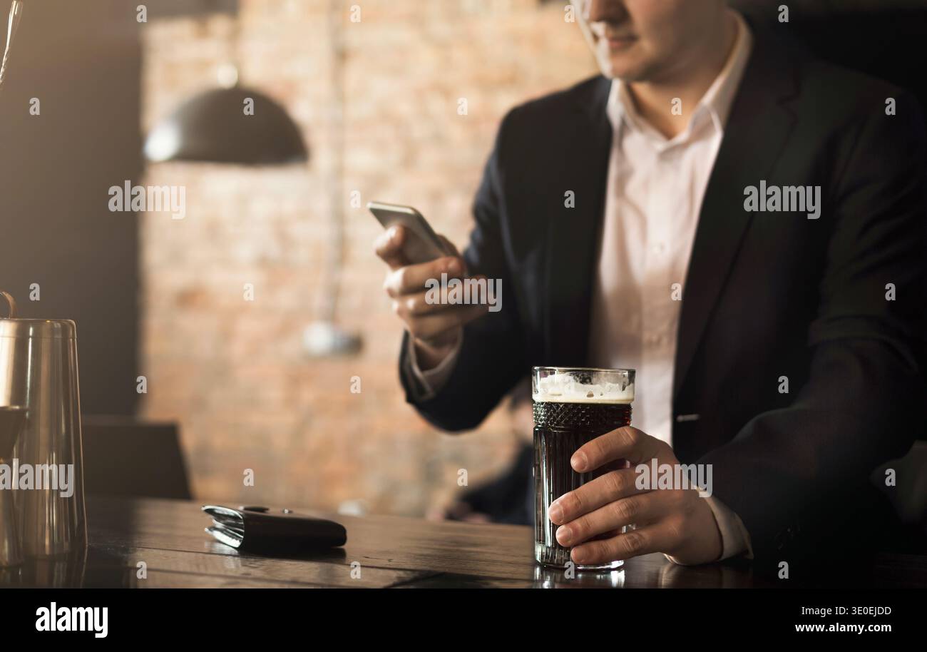 Young man sitting at bar counter and using smartphone Stock Photo