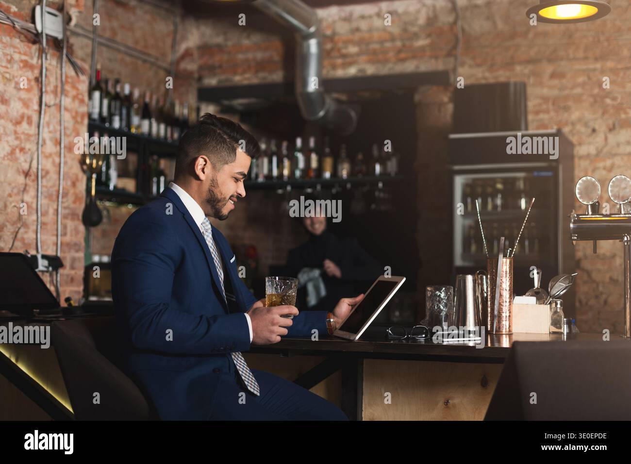 Young man sitting at bar counter and using digital tablet Stock Photo