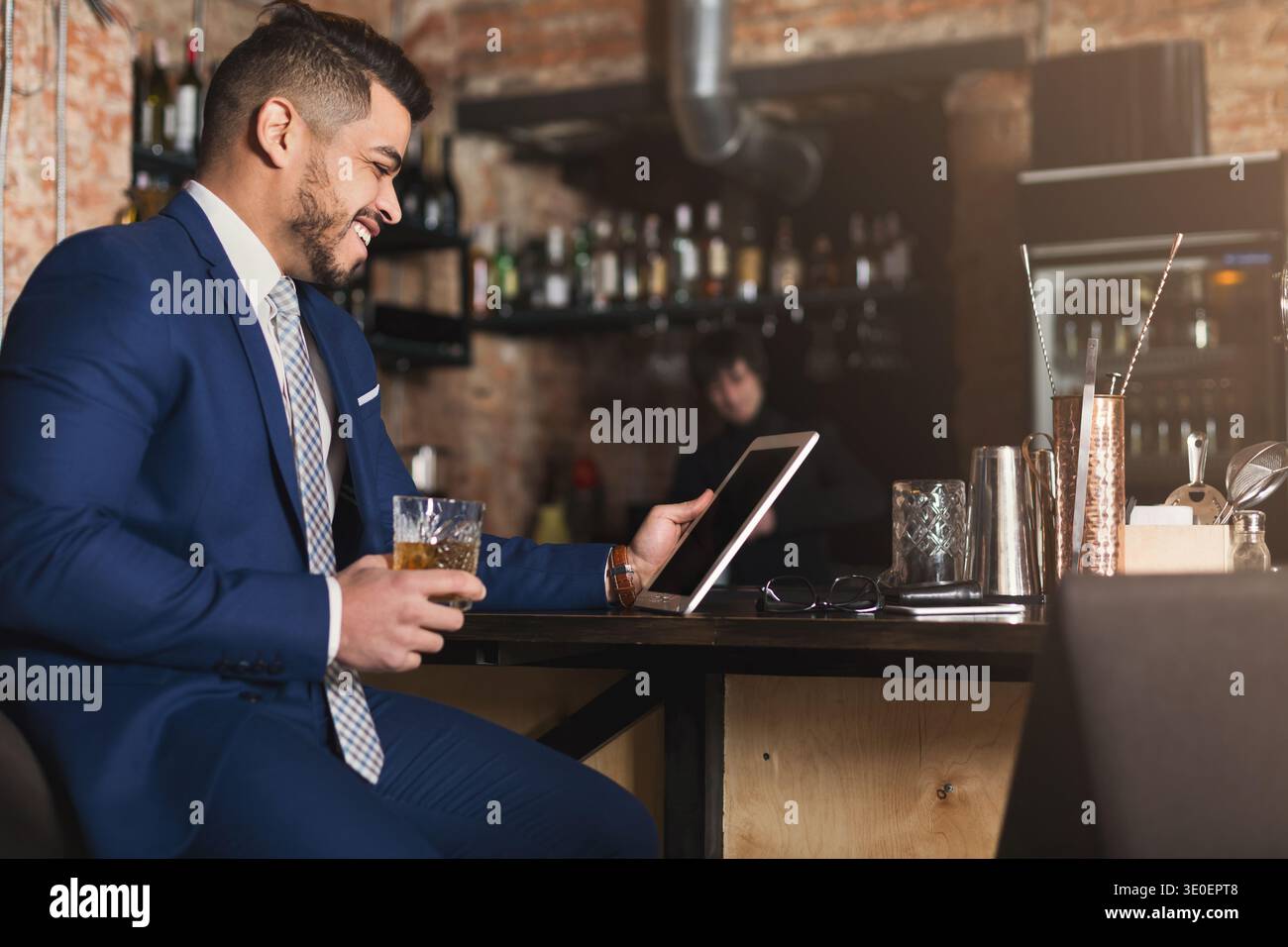 Young man sitting at bar counter and using digital tablet Stock Photo