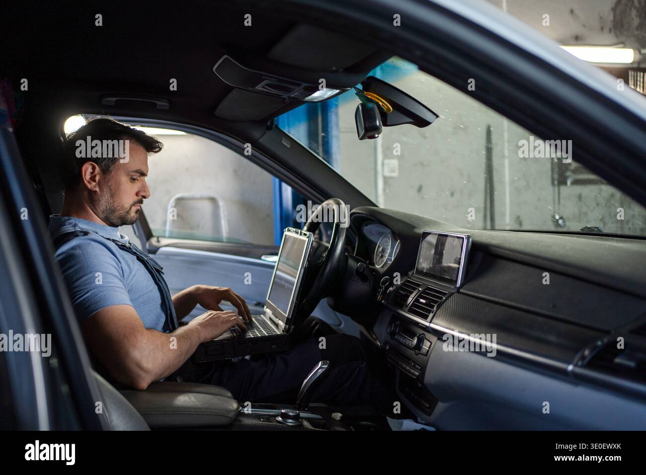 Car mechanic using laptop for diagnostics inside a vehicle Stock Photo