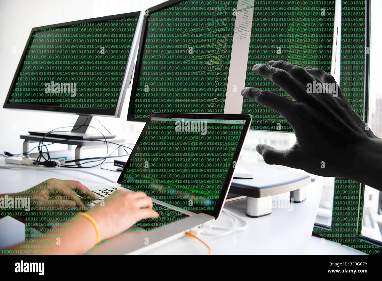 Hacker Reaching Over Laptop With Multiple Monitors Showing Green Binary Code Representing Cybersecurity Breach Stock Photo