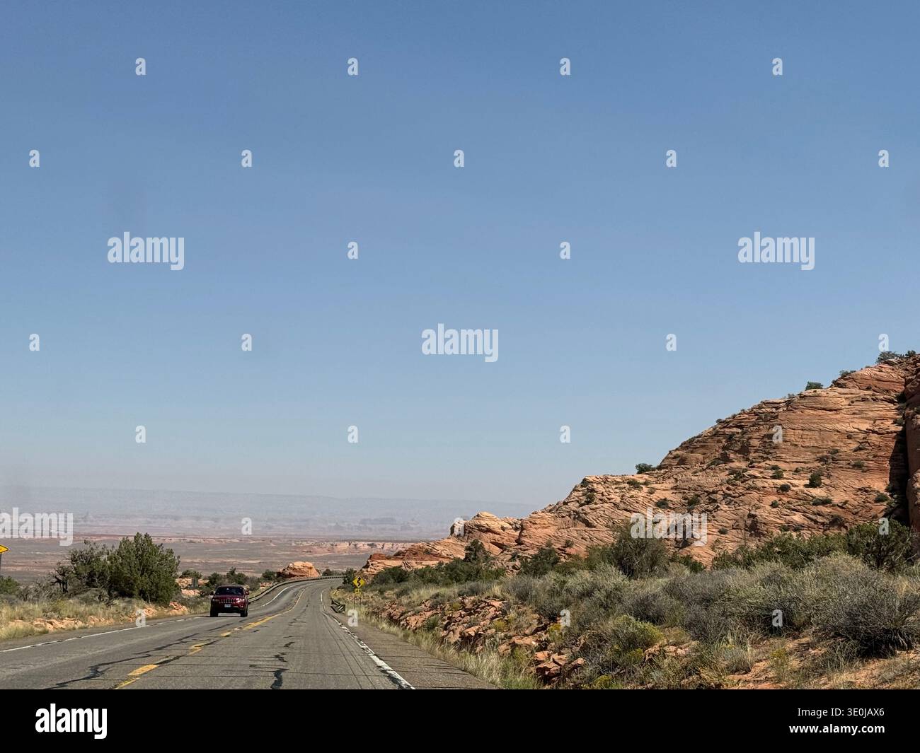 Desert highway winding through red rock formations and rugged landscape in the American Southwest, Utah, USA. - Smartphone Captured Stock Image