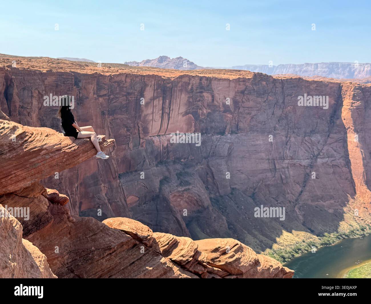Woman sitting on cliff edge overlooking vast canyon landscape in the American Southwest, Utah, USA. - Smartphone Captured Stock Image