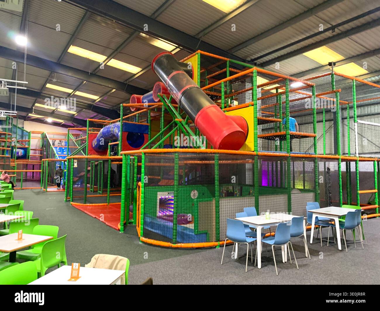 Indoor family entertainment centre with dinning tables in the foreground and a large multi level soft play structure in the background in Yorkshire - Smartphone Captured Stock Image
