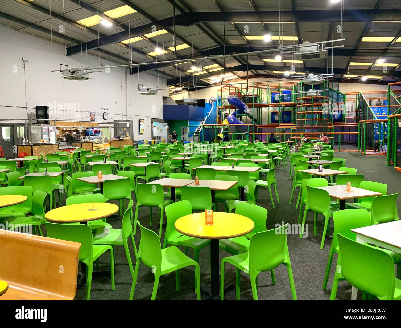 Indoor family entertainment centre with dinning tables in the foreground and a large multi level soft play structure in the background in Yorkshire - Smartphone Captured Stock Image