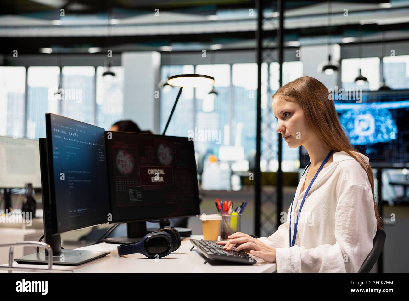 Young inexperienced programmer in office struggling to fix critical error warning popup. Tech startup intern troubleshooting error notification on PC screen interrupting workflow Stock Photo