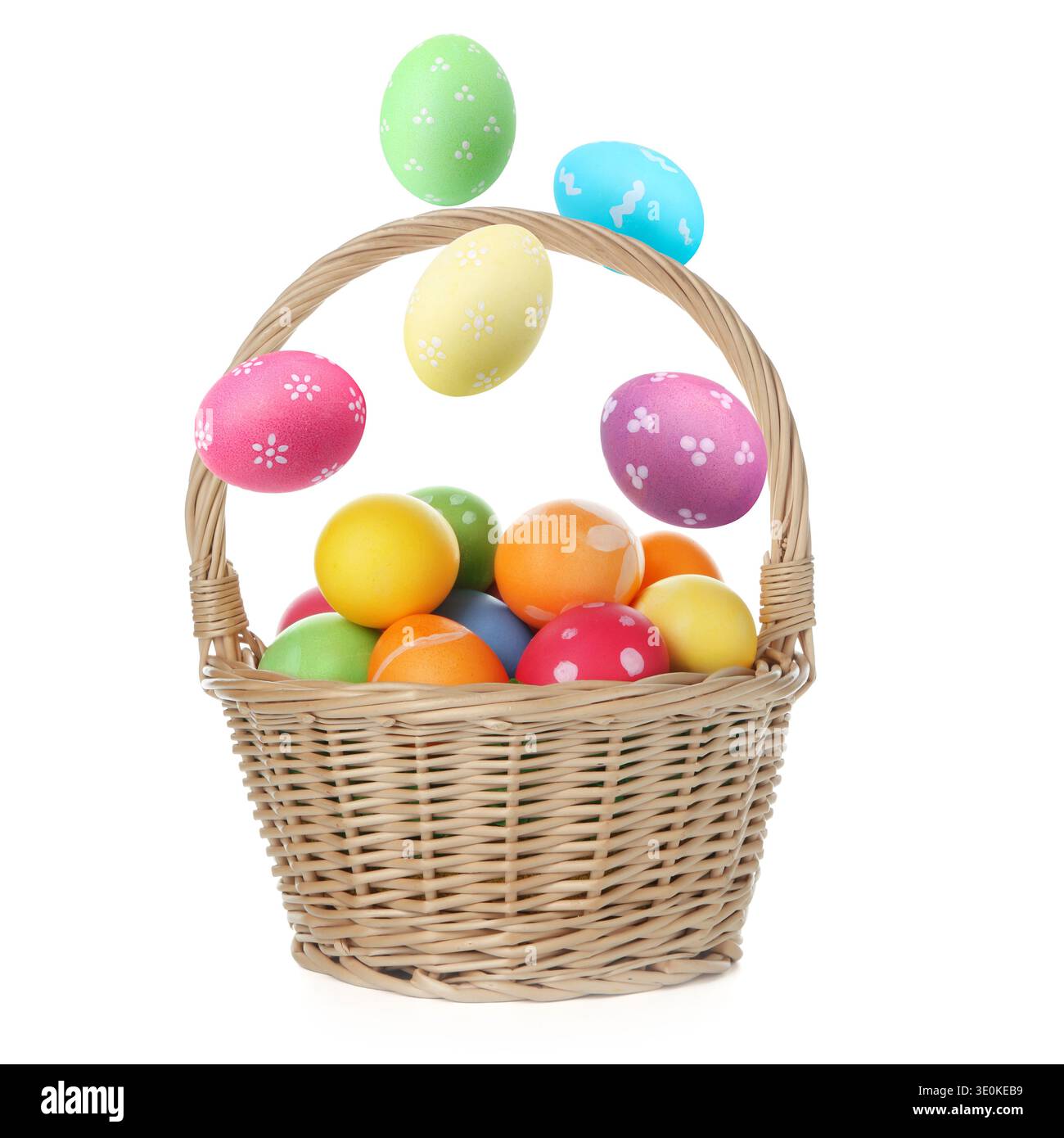 Bright Easter eggs falling into basket on white background Stock Photo