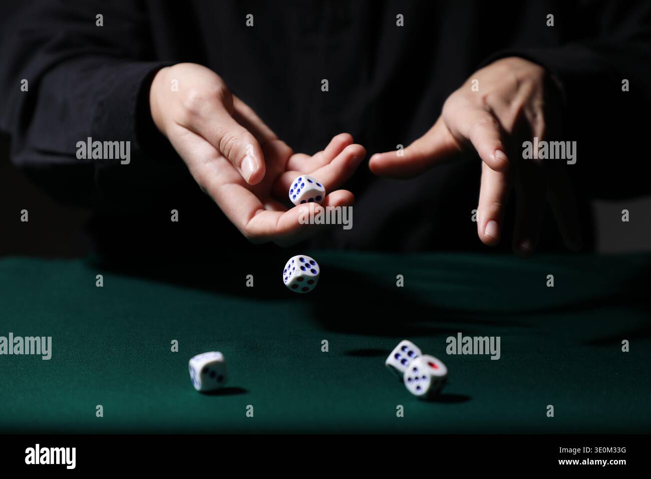 Man throwing white game dices on green table, closeup Stock Photo