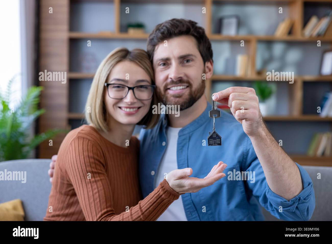 Smiling young couple embracing and celebrating new home ownership ...