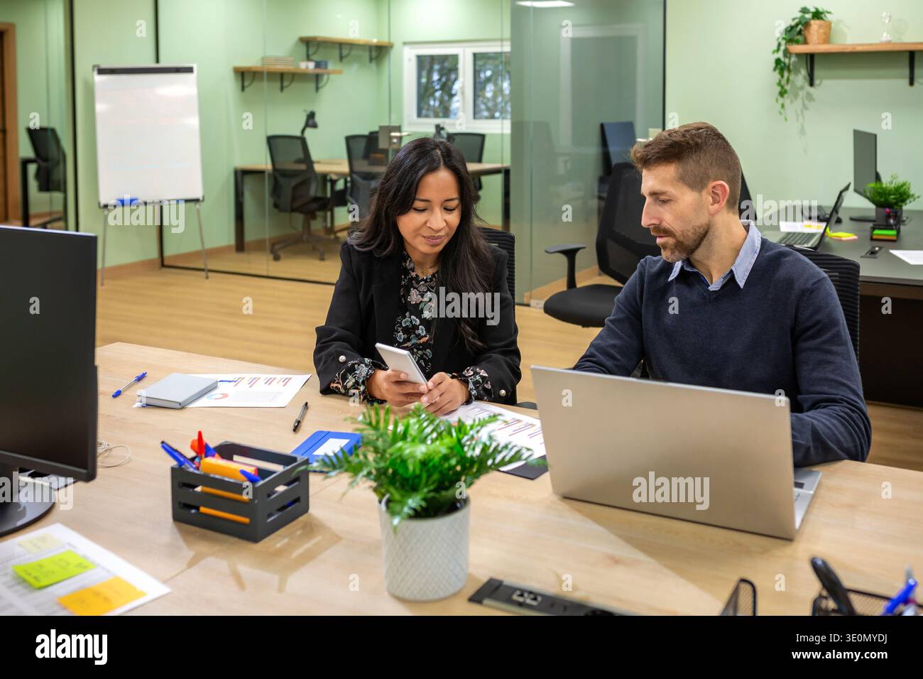 Diverse business professionals using technologies while collaborating in modern coworking office Stock Photo