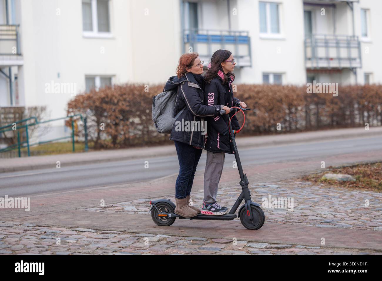 26.02.2026 - Zwei Frauen fahren auf einen E-Roller illigal den Fußweg entlang. das ist verboten Torgelow Mecklenburg-Vorpommern Deutschland *** 26 02 2026 Two women riding an electric scooter illigal along the sidewalk that is forbidden Torgelow Mecklenburg Vorpommern Germany Stock Photo