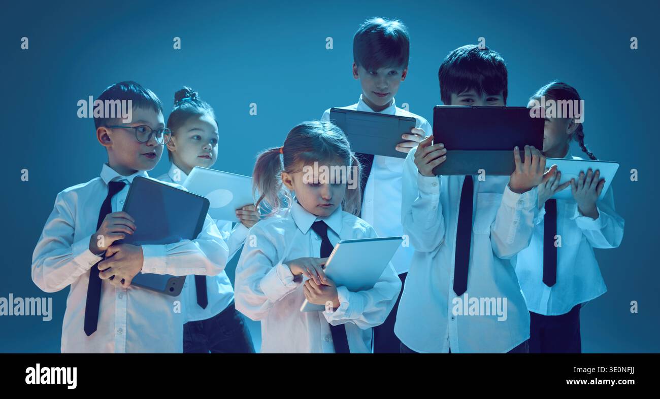 Kids using tablet devices together in neon studio Stock Photo