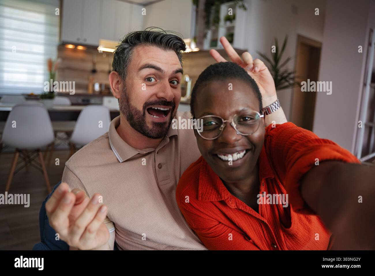 Playful Couple Taking a Selfie at Home, Making Funny Faces Stock Photo