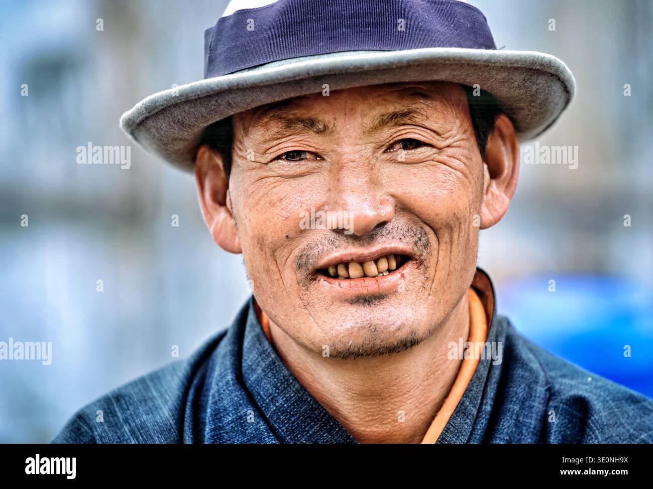 A man wearing traditional clothes and a hat smiles while posing for a portrait in Bhutan. His warm expression captures a moment of joy. Stock Photo