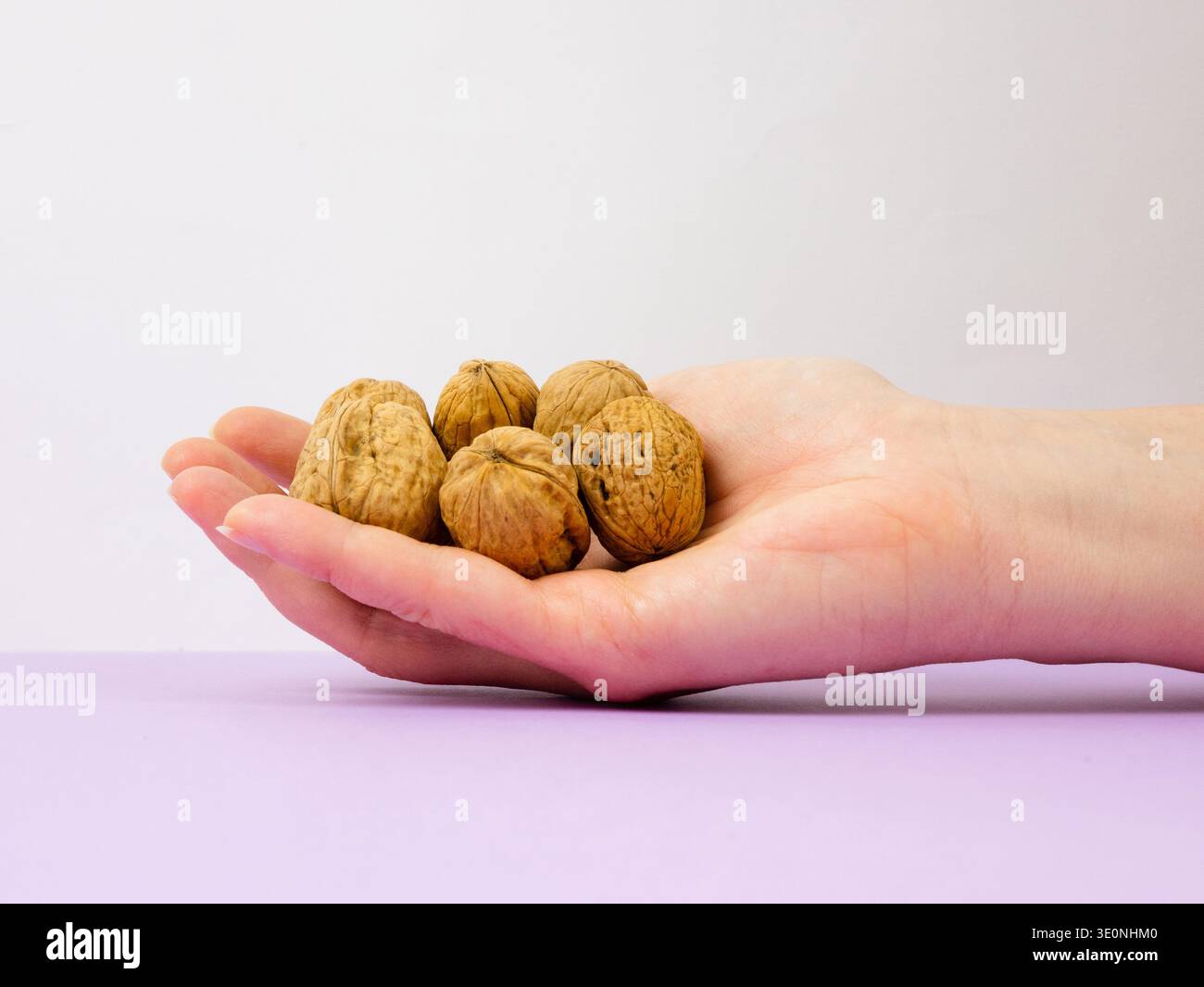 Hand holding several whole walnuts Stock Photo