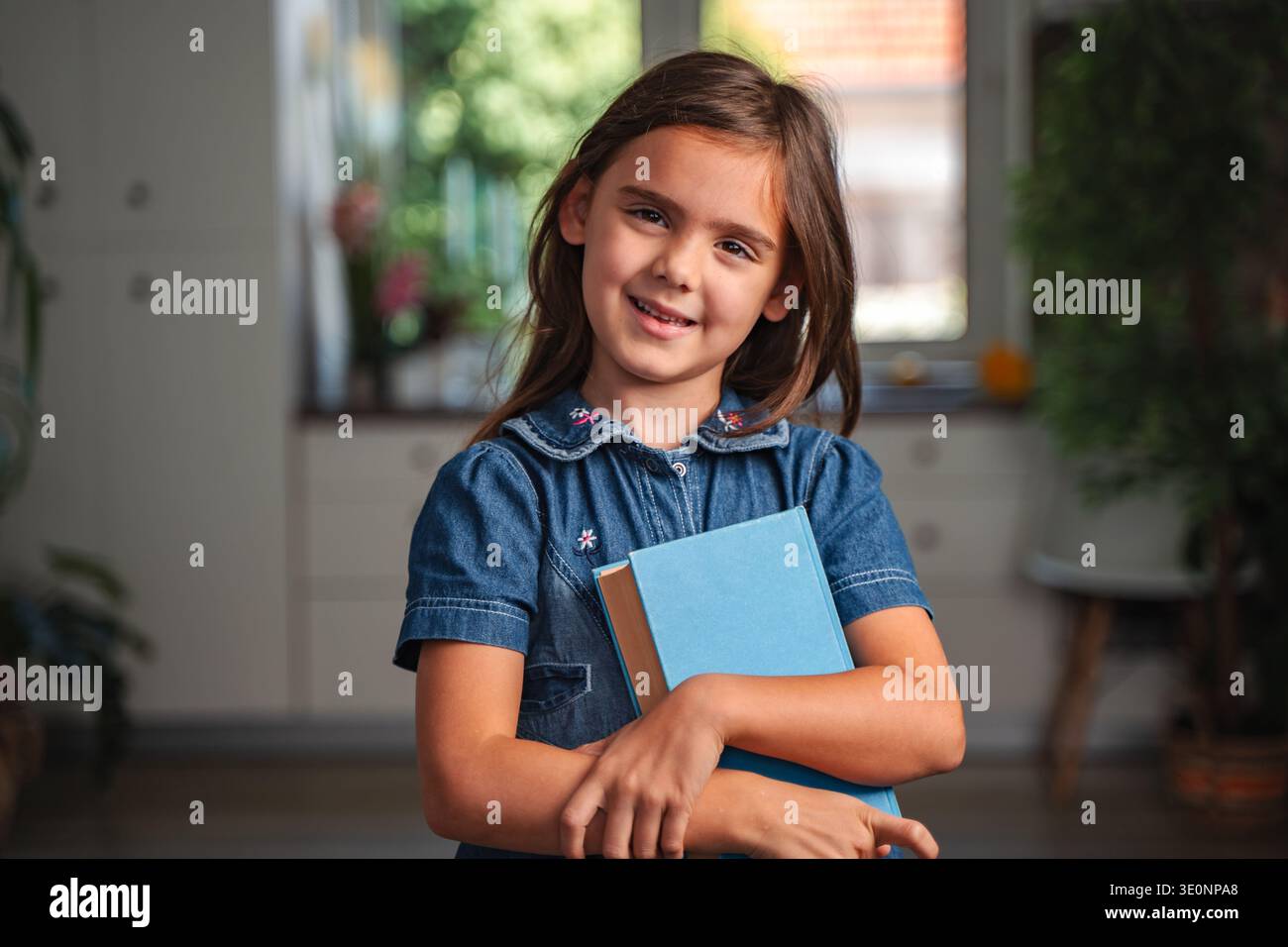 Portrait of smiling schoolgirl holding books at home Stock Photo - Alamy