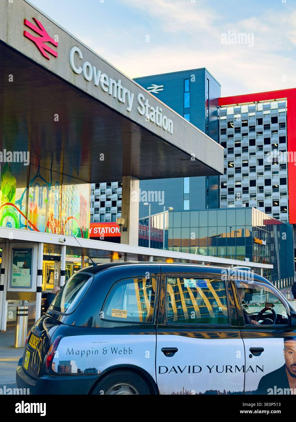 Black taxi cab parked outside the modern exterior of Coventry railway Station with contemporary buildings in the urban environment - Smartphone Captured Stock Image