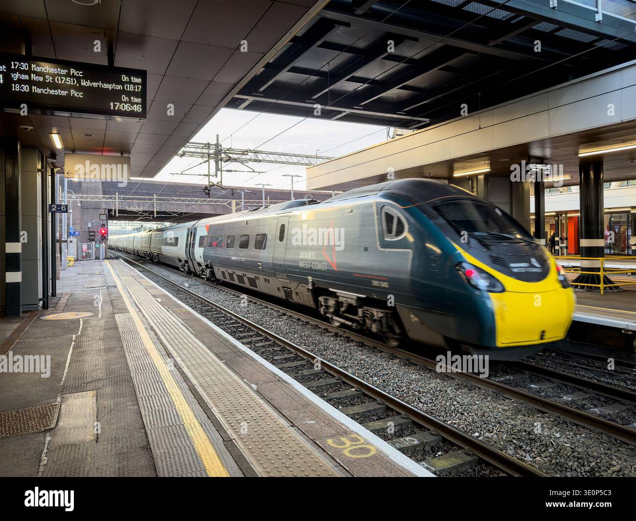 Modern electric avanti pendolino 390 class train moving through a covered railway station platform with departure board visible coventry uk - Smartphone Captured Stock Image