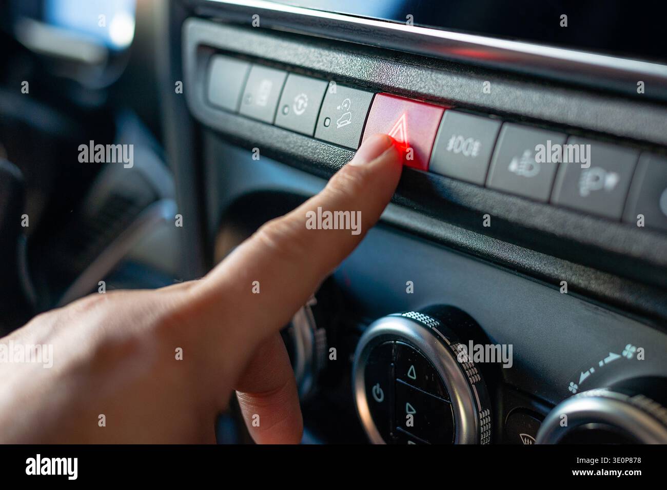 Close up of the red triangle hazard button being pressed on a vehicle console during an emergency or stop. Stock Photo
