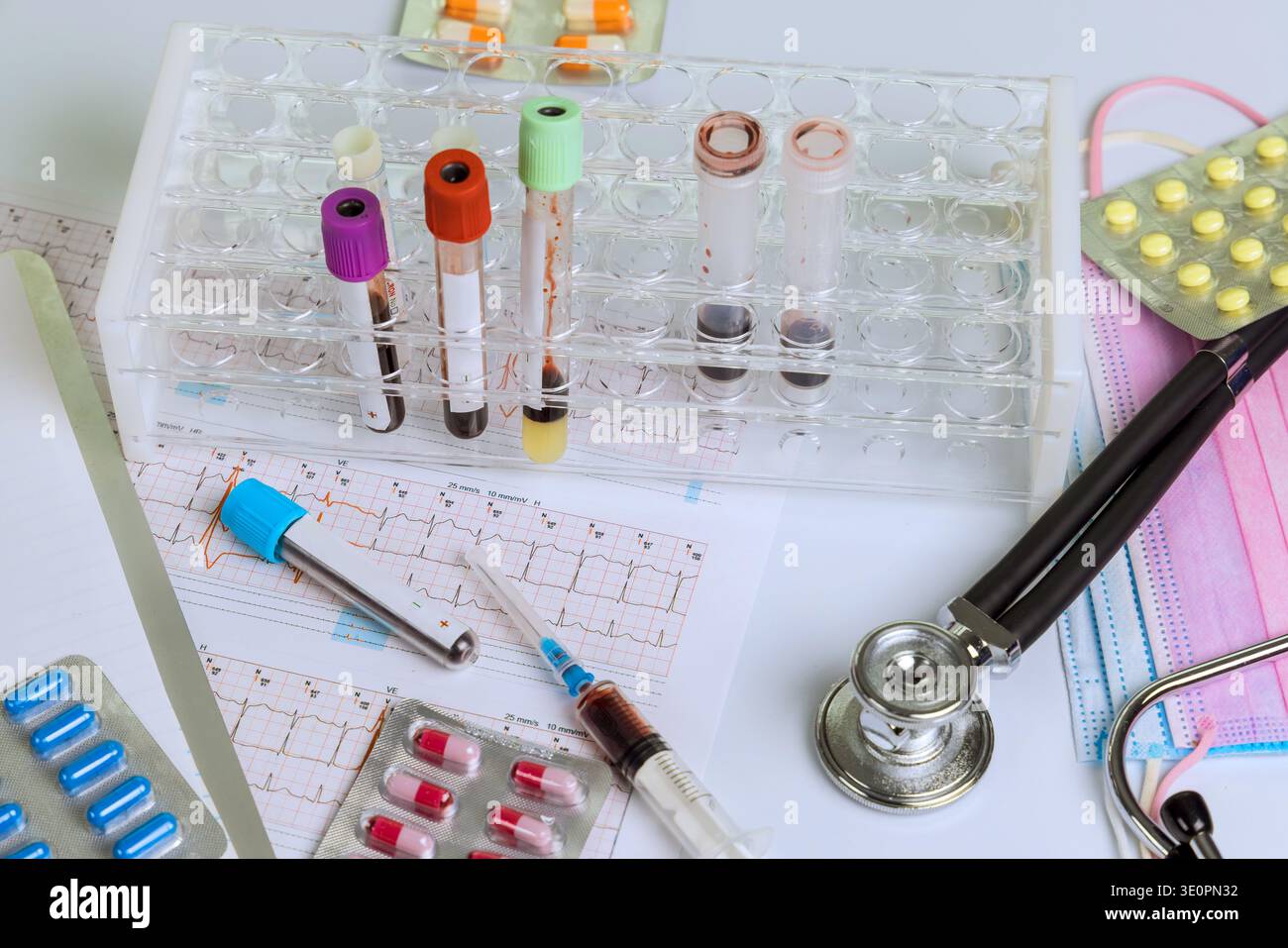 Various medical tools, blood samples, medication are arranged on work surface for heart chart testing Stock Photo