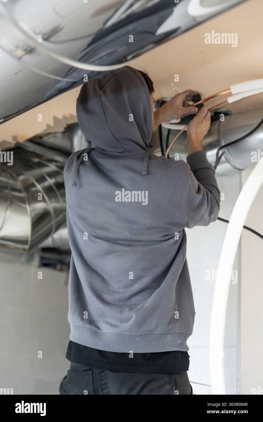 Air conditioning technician installing and connecting copper pipes within a new construction or renovation, focusing on hvac system components for cli Stock Photo