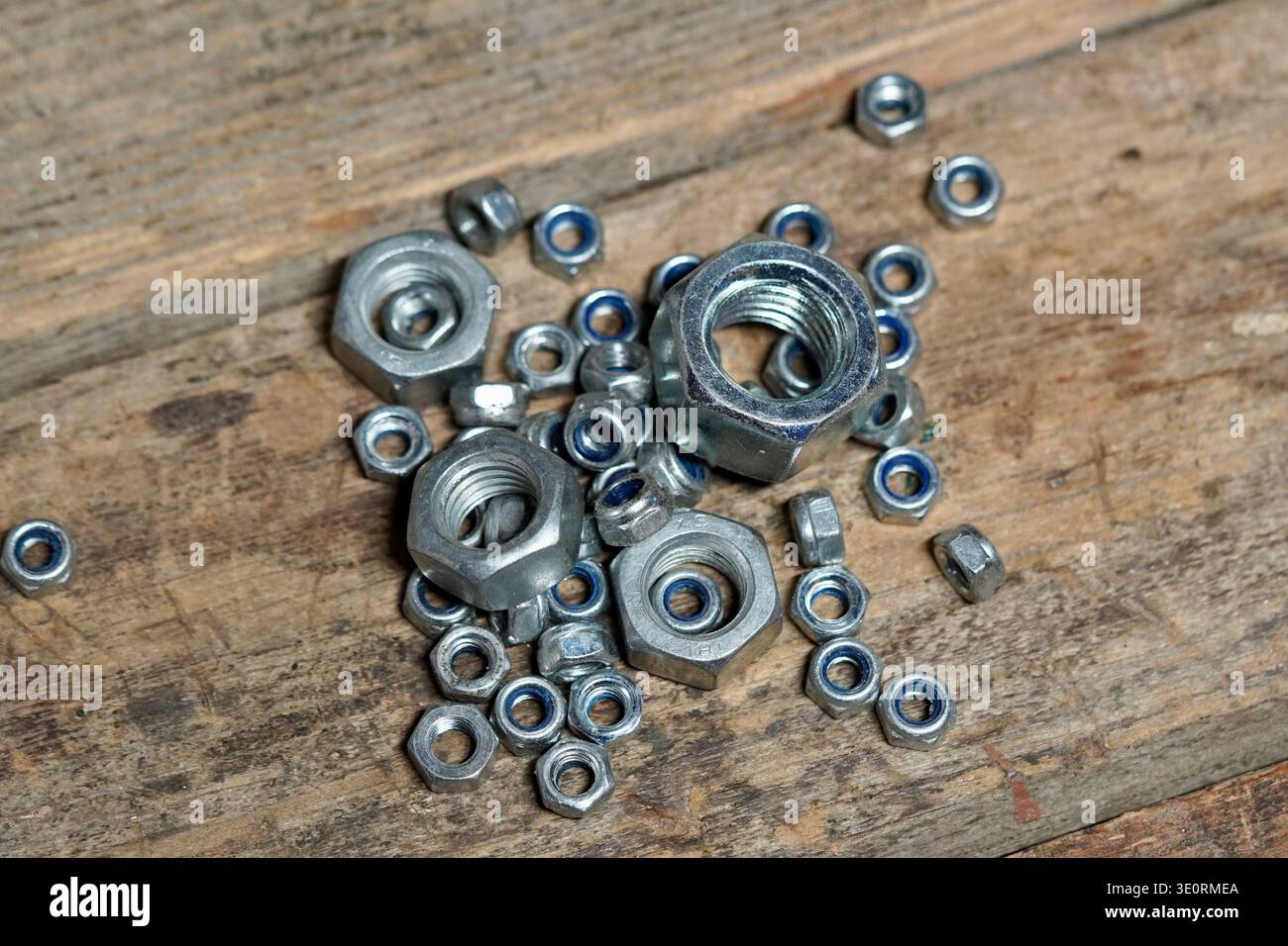 'Oh nuts' concept using nuts hardware spilled on a rustic wood work bench Stock Photo