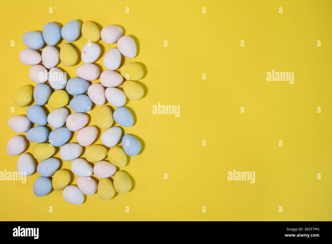 Pastel Easter eggs on yellow background with copy space Stock Photo
