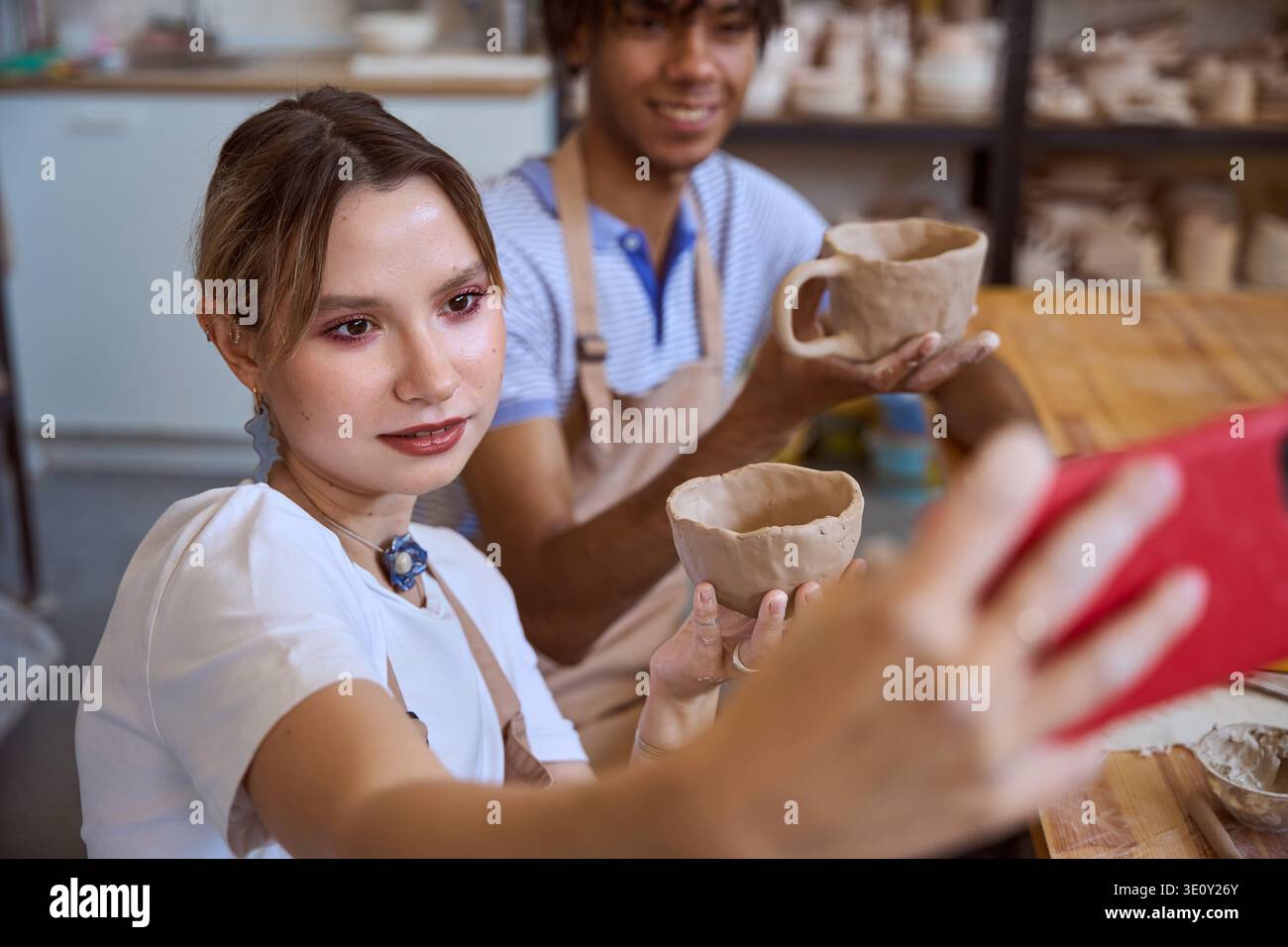 Young adults taking joyful selfie in pottery studio Stock Photo