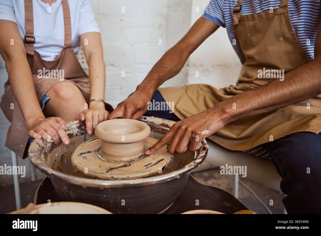 Diverse adults working on pottery wheel in creative studio Stock Photo