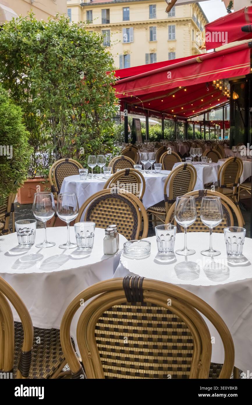 Outdoor Restaurant Setting with Red Awnings and Wicker Chairs Stock Photo