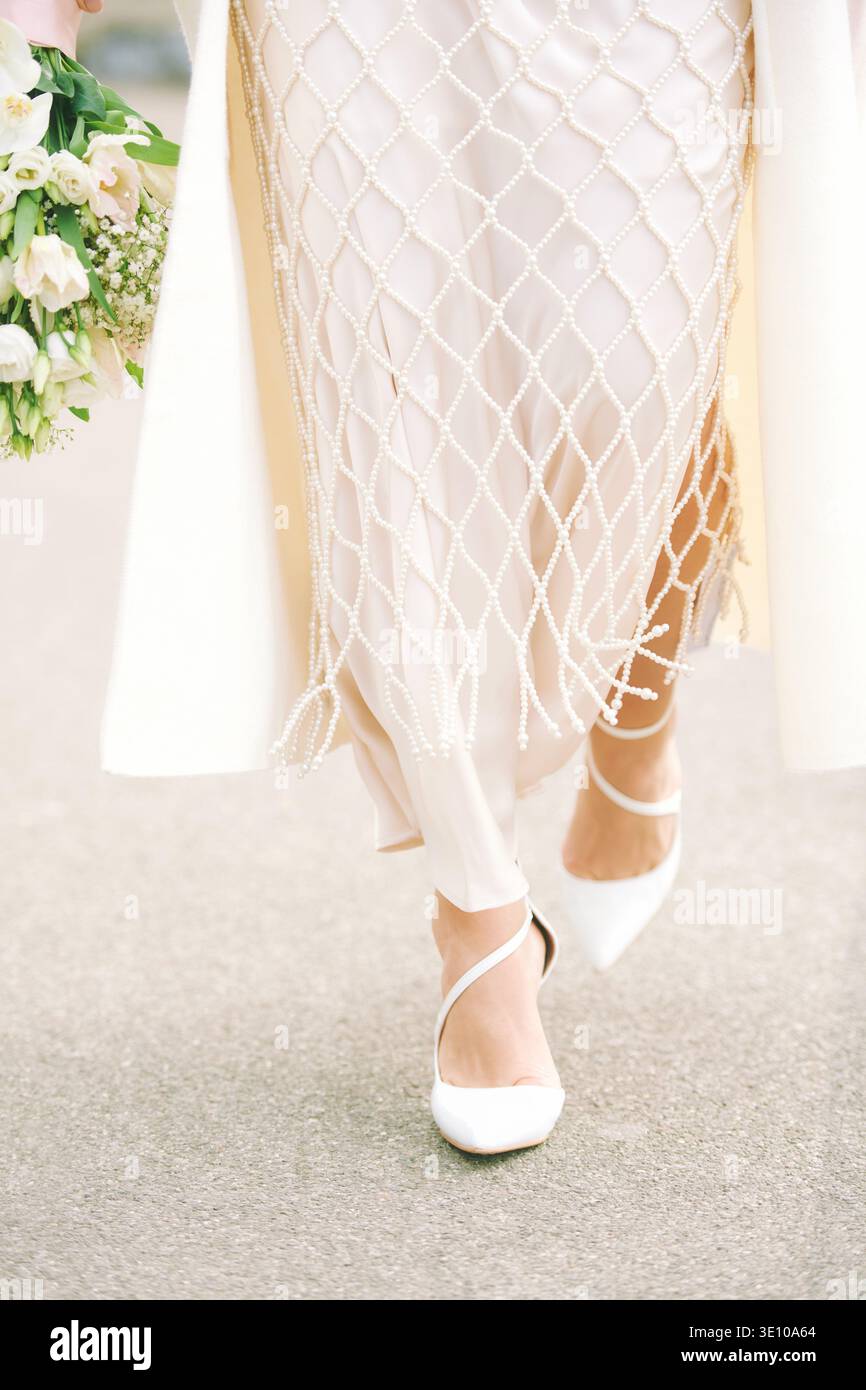 Bride walking in elegant white dress with pearl details and bouquet, close view of wedding shoes and flowers, romantic bridal fashion moment on sunny Stock Photo - Alamy Bride walking in elegant white dress with pearl details and bouquet, close view of wedding shoes and flowers, romantic bridal fashion moment on sunny Stock Photo - Alamy