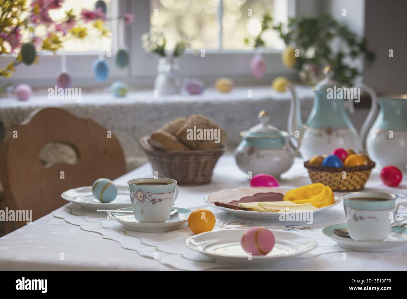 Decorated table with colorful easter eggs, pastries and cold platter Stock Photo
