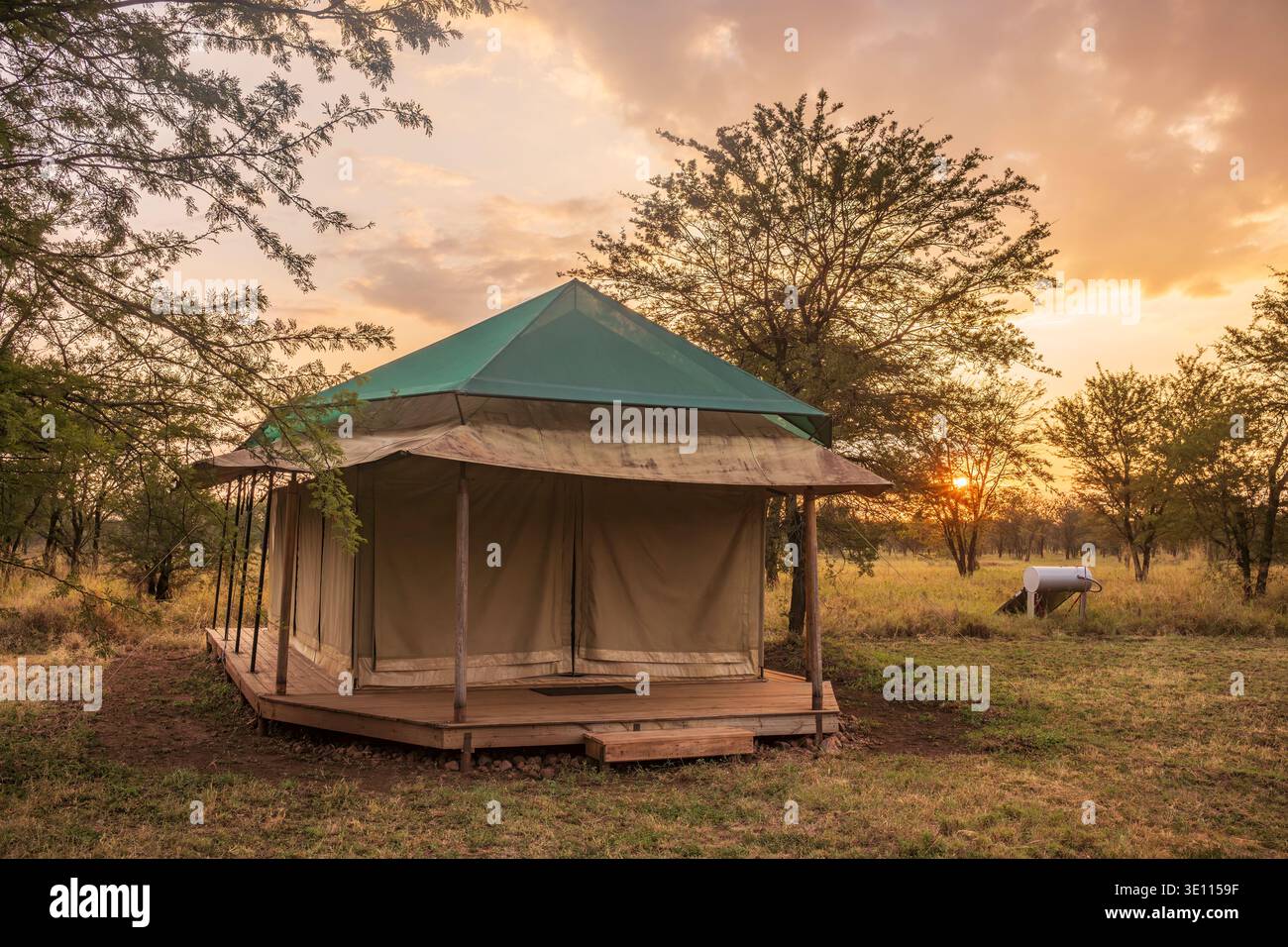 The sun rises behind a tent located at a camp for tourists at Central Serengeti National Park, Tanzania. Stock Photo