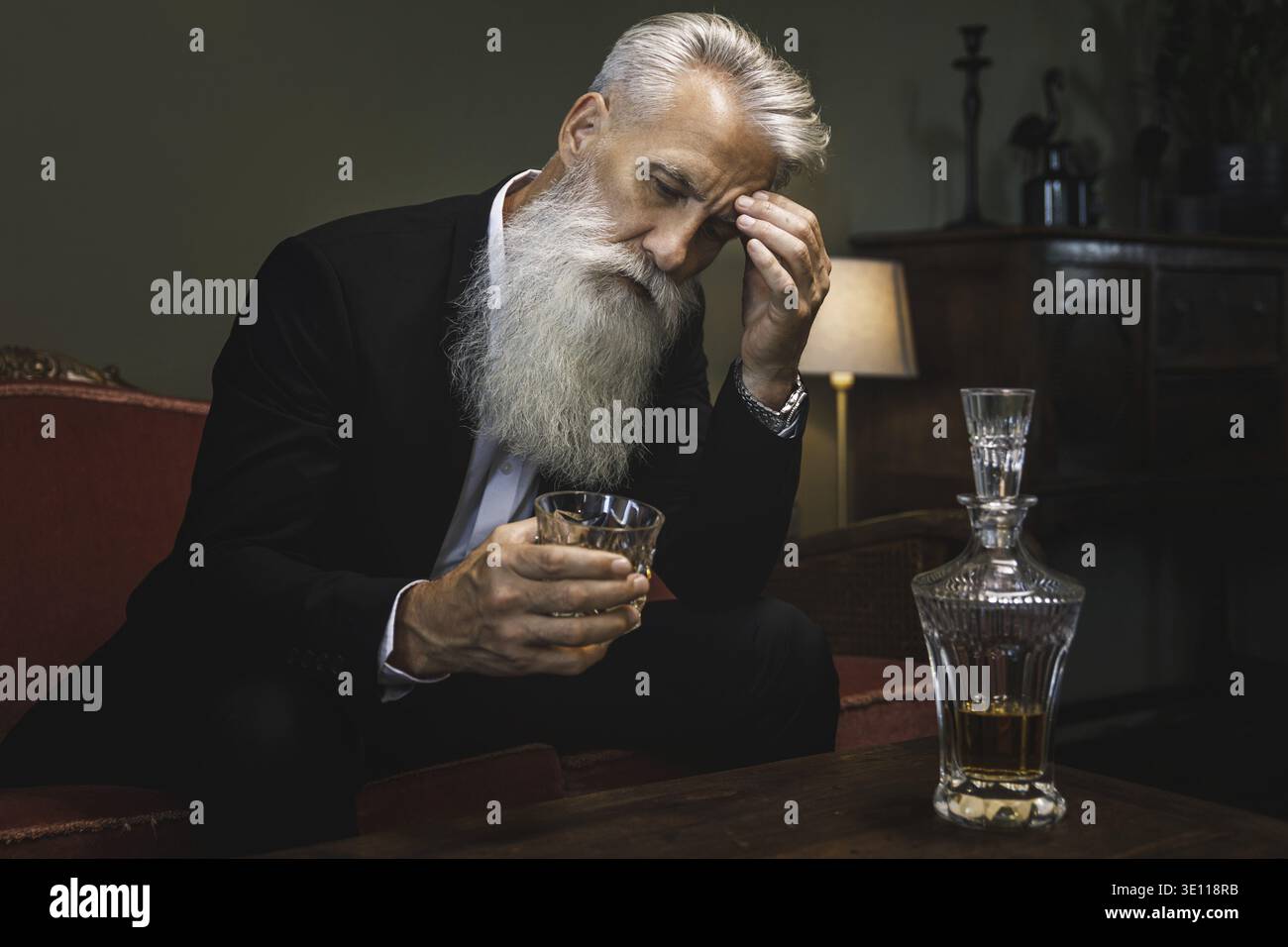 Stylish and handsome bearded senior man drinking whiskey Stock Photo
