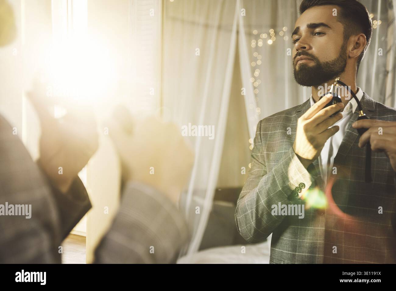 Young and handsome bearded man is using atomizer nozzle with perfume Stock Photo