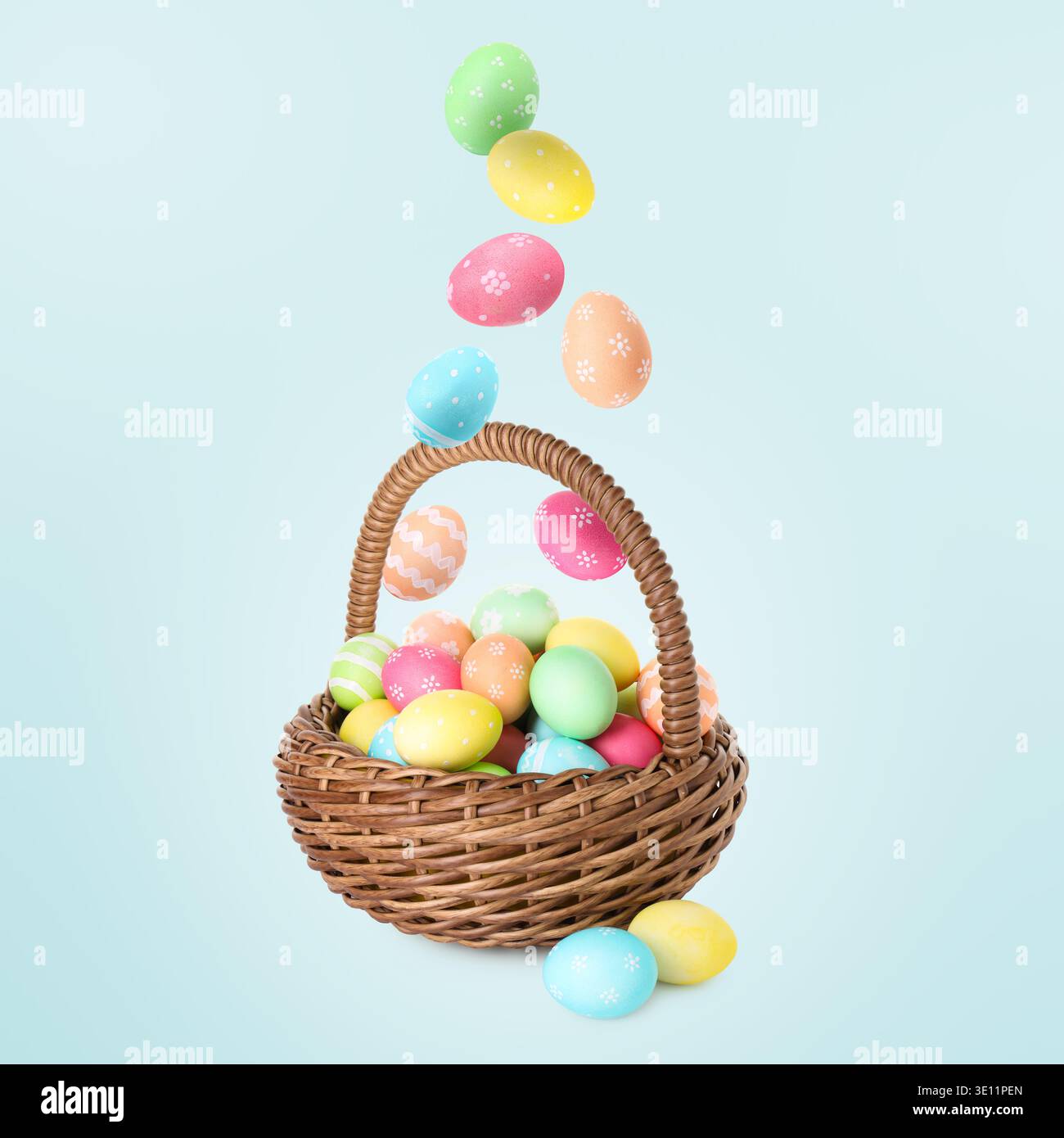 Color Easter eggs falling into basket on light blue gradient background Stock Photo