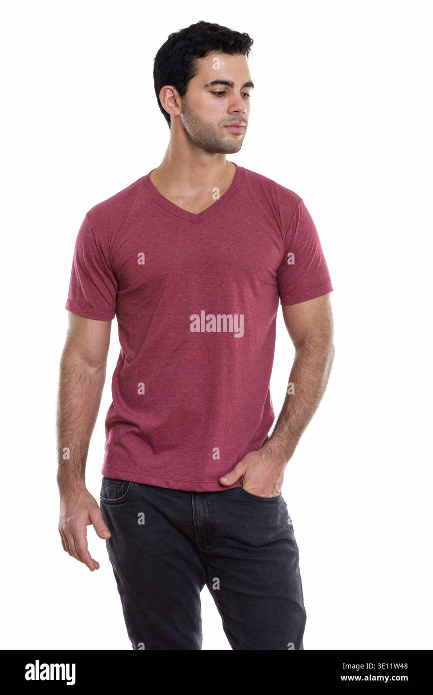 Studio shot of young handsome Hispanic man posing while thinking and looking down Stock Photo