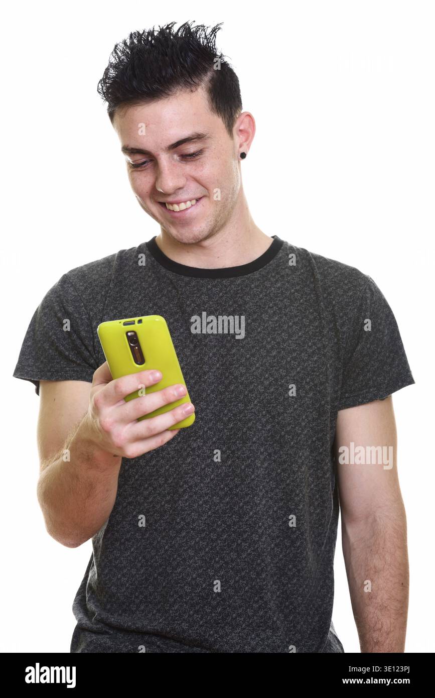 Studio shot of happy young man smiling while using mobile phone Stock Photo