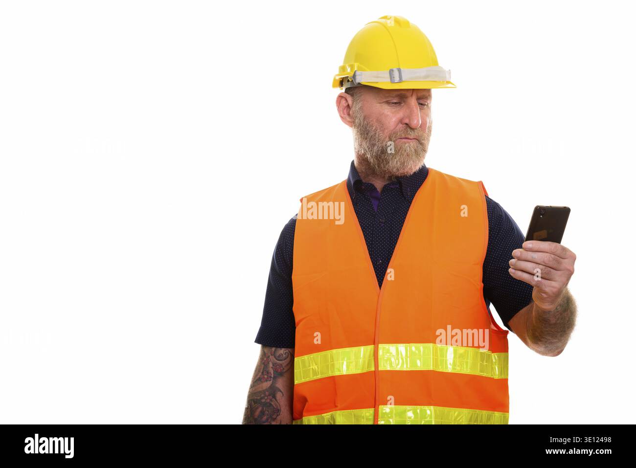 Mature bearded man construction worker with hand tattoos using mobile phone Stock Photo