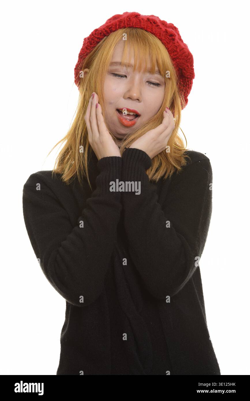 Young happy Asian woman smiling with closed eyes while touching her face Stock Photo