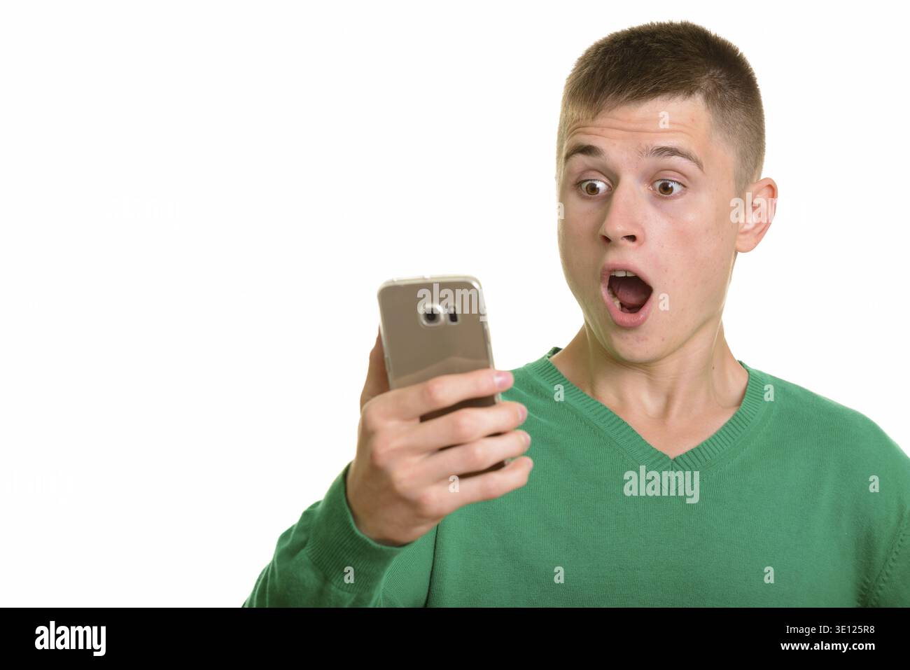 Young Caucasian man holding mobile phone looking surprised isolated against white background Stock Photo
