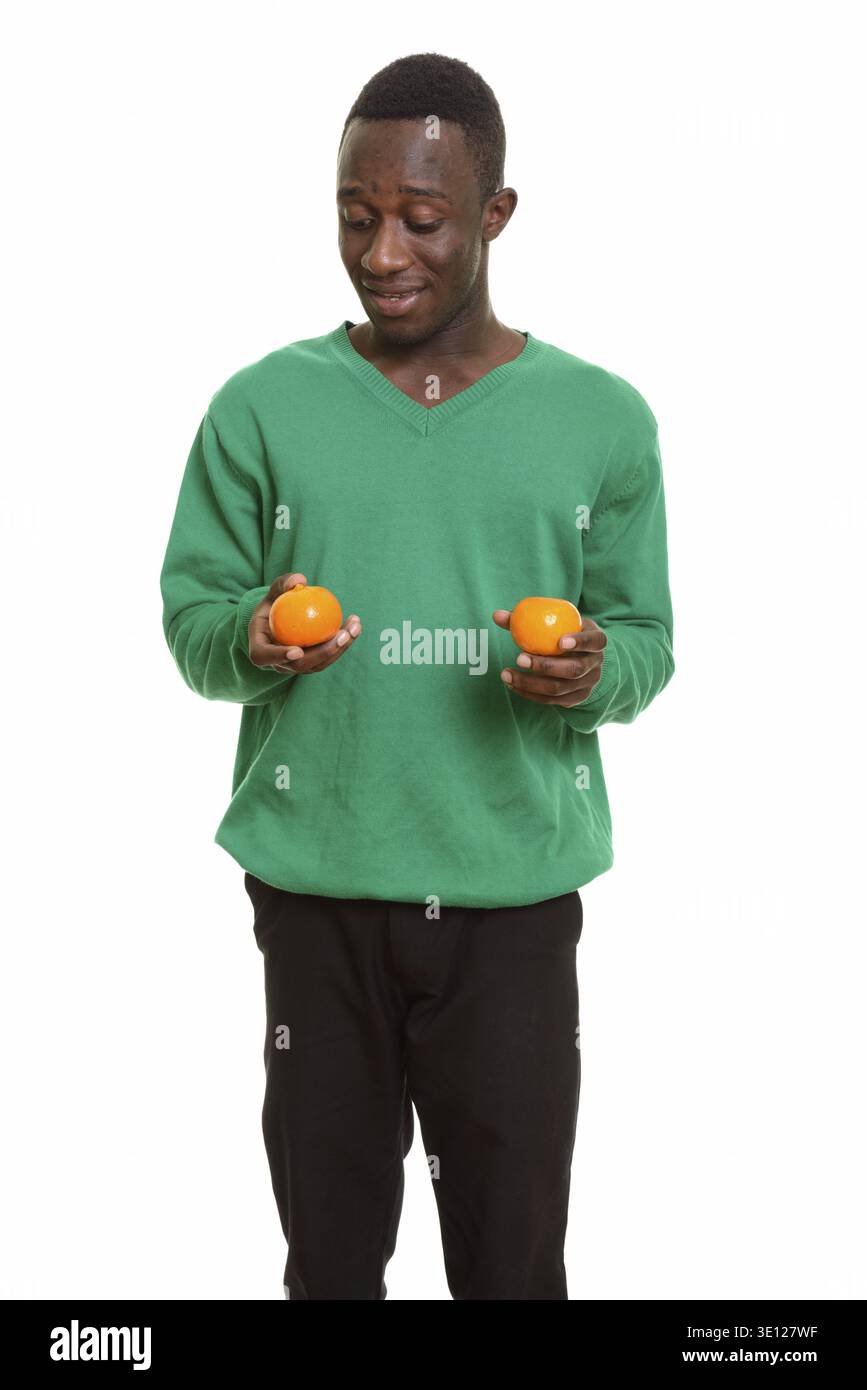 Young happy African man smiling and holding two oranges isolated against white background Stock Photo