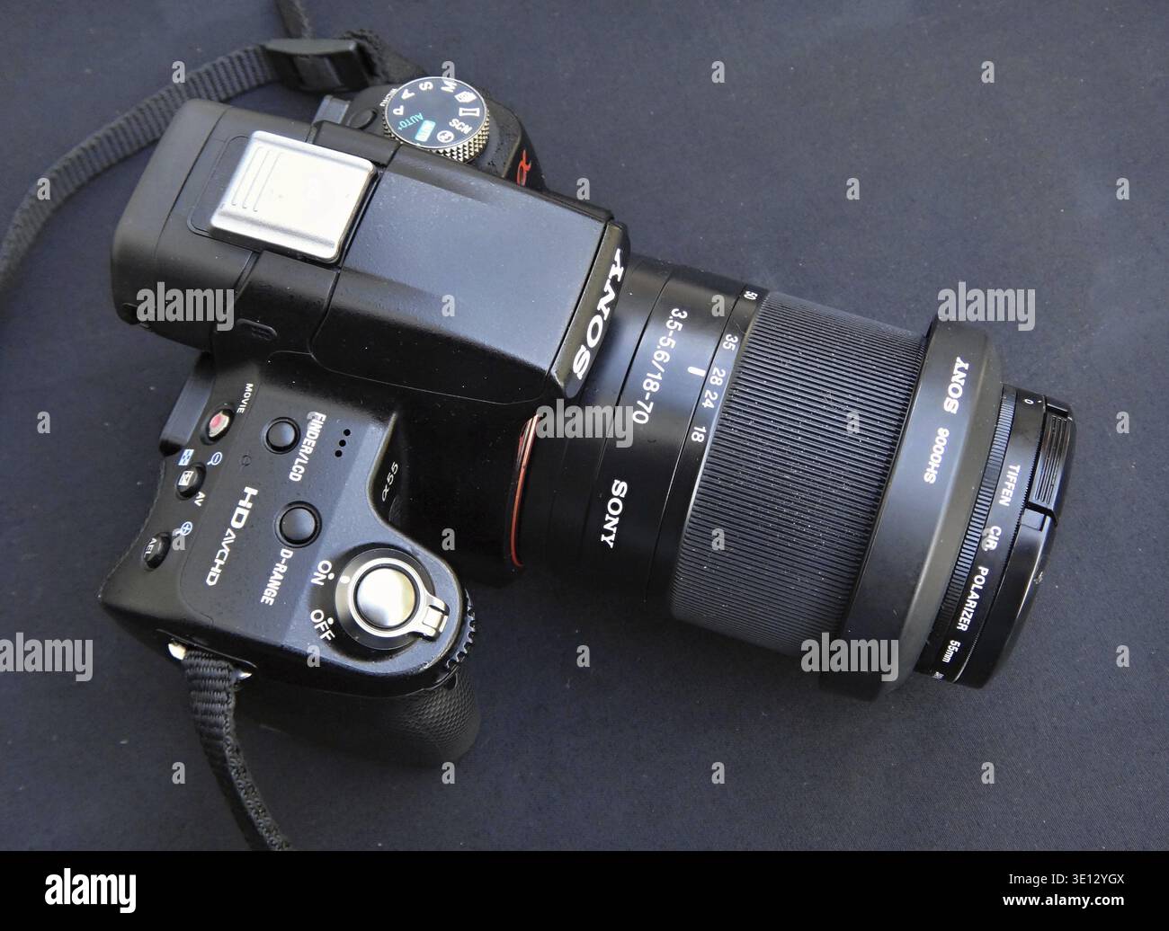 Sony Alpha camera with a polarizing filter attached to the lens, lying on a dark surface, ready for shooting Stock Photo