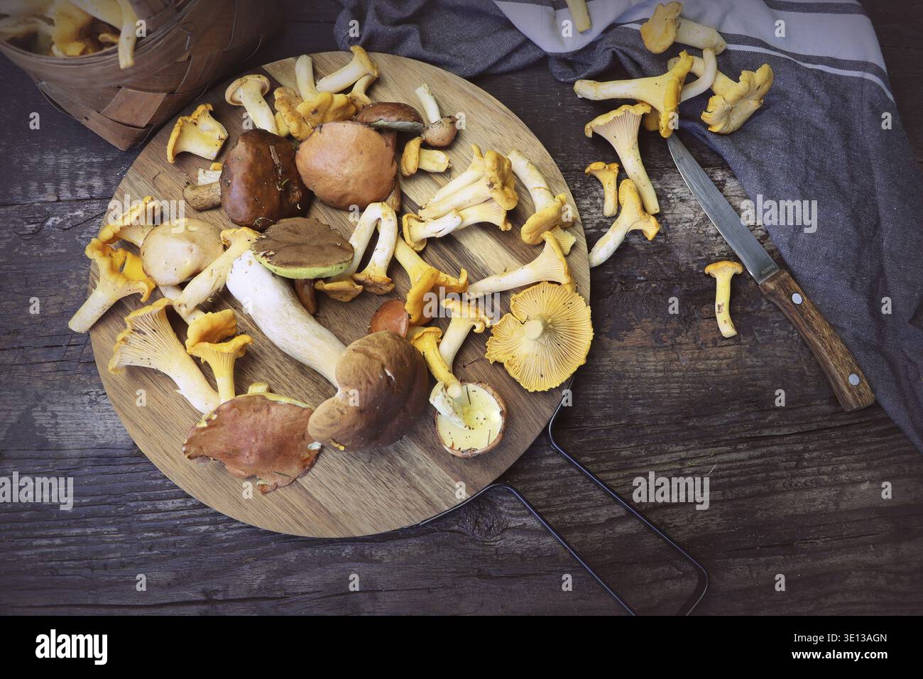 Mix of forest mushrooms on cutting board over old wooden table Stock Photo