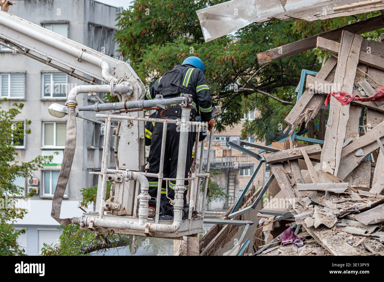 Rescue workers clearing rubble at damaged building site using aerial platform Stock Photo