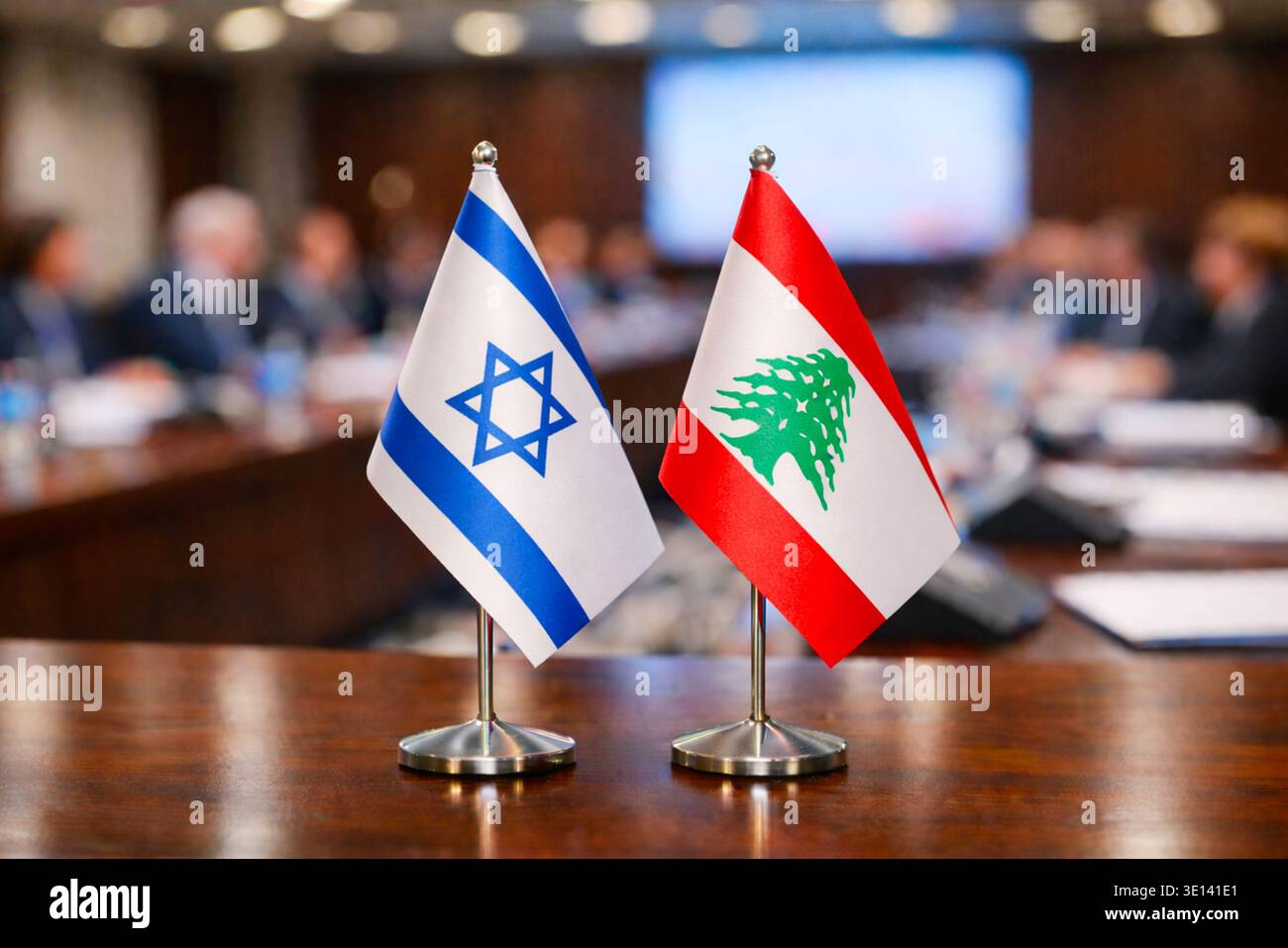 Two small national flags of Israel and Lebanon placed on a conference table with a blurred meeting room in the background Stock Photo
