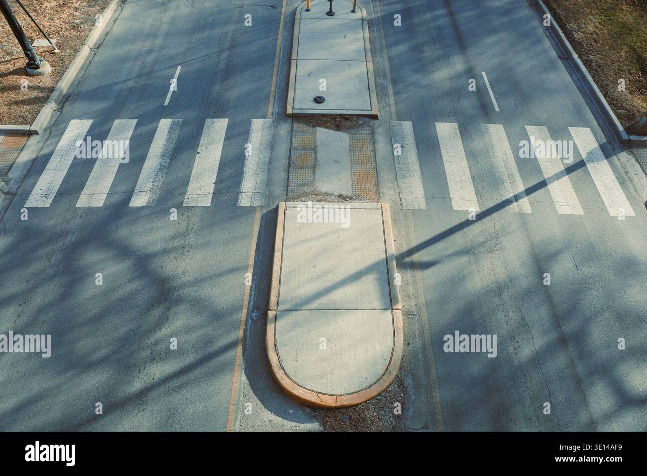 A road crossing has marked pedestrian pathways at the center. Shadows ...