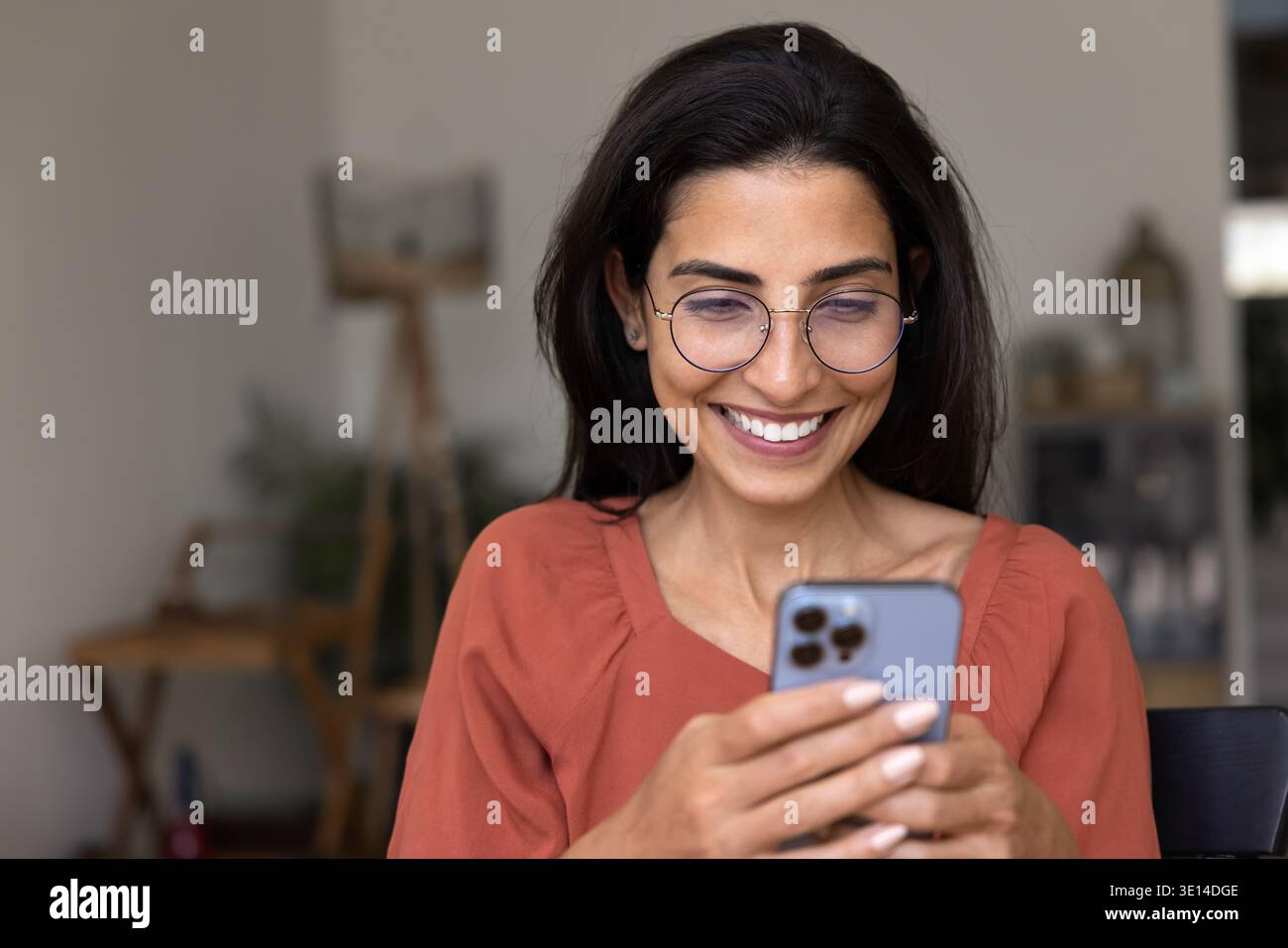 Happy Brazilian woman using smartphone at home Stock Photo